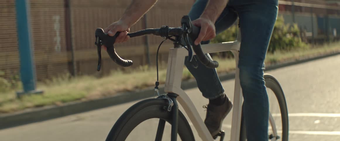 Man rides a bicycle over a road in an industrial part of town