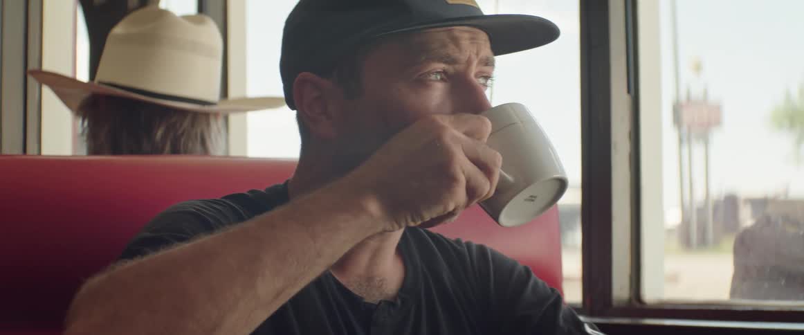 Man sitting in a restaurant next to the window drinking a cup of coffee