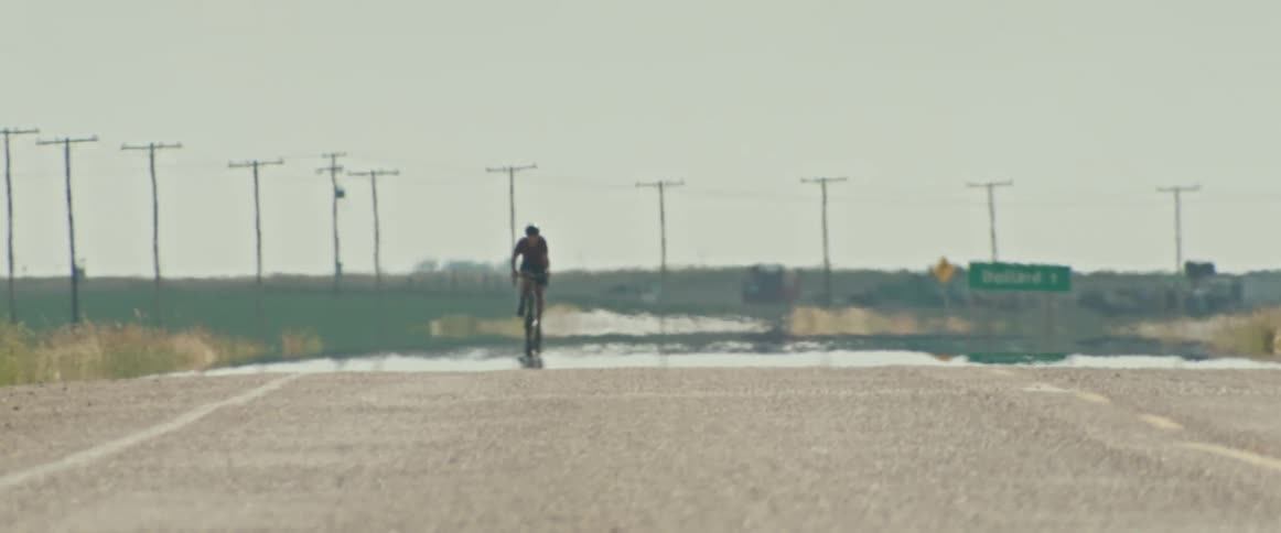 Cyclist rides a bicycle over the asphalt on a hot road in the daytime