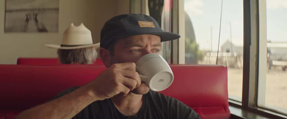 A man sits in a diner and sips a cup of coffee