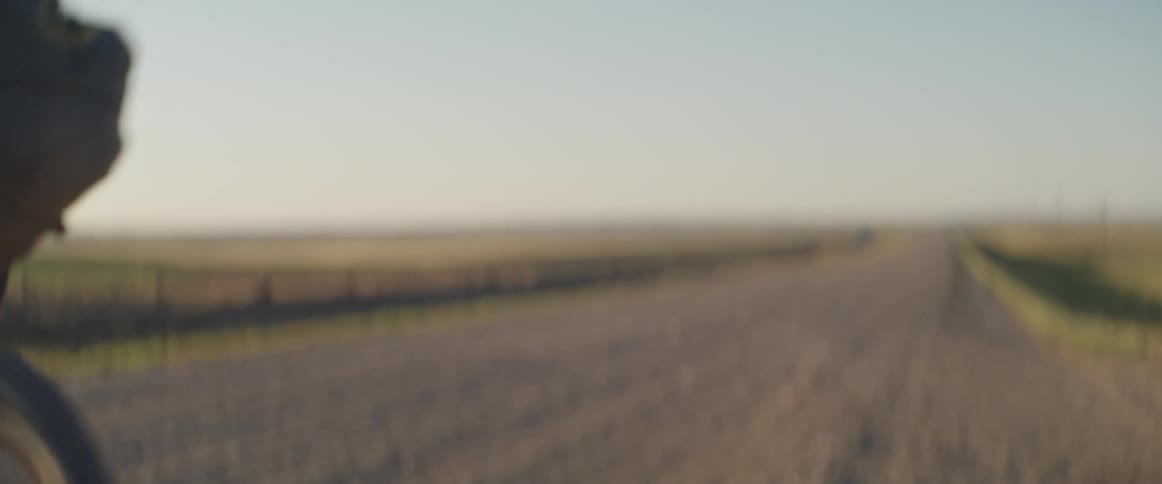 A man sets off on his bike down a rural dirt road
