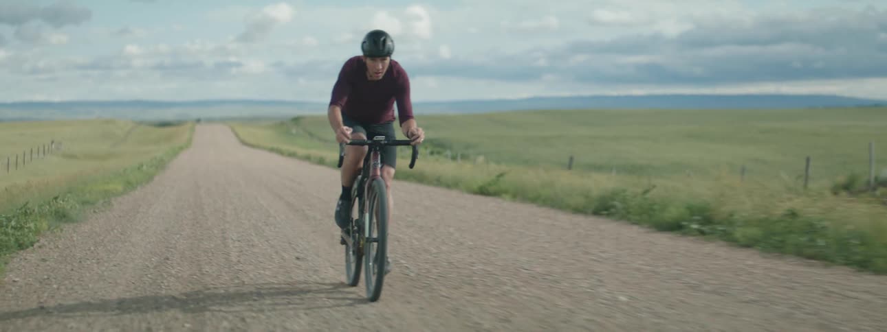 Man rides a bicycle on a dirt road on a rural area at daytime