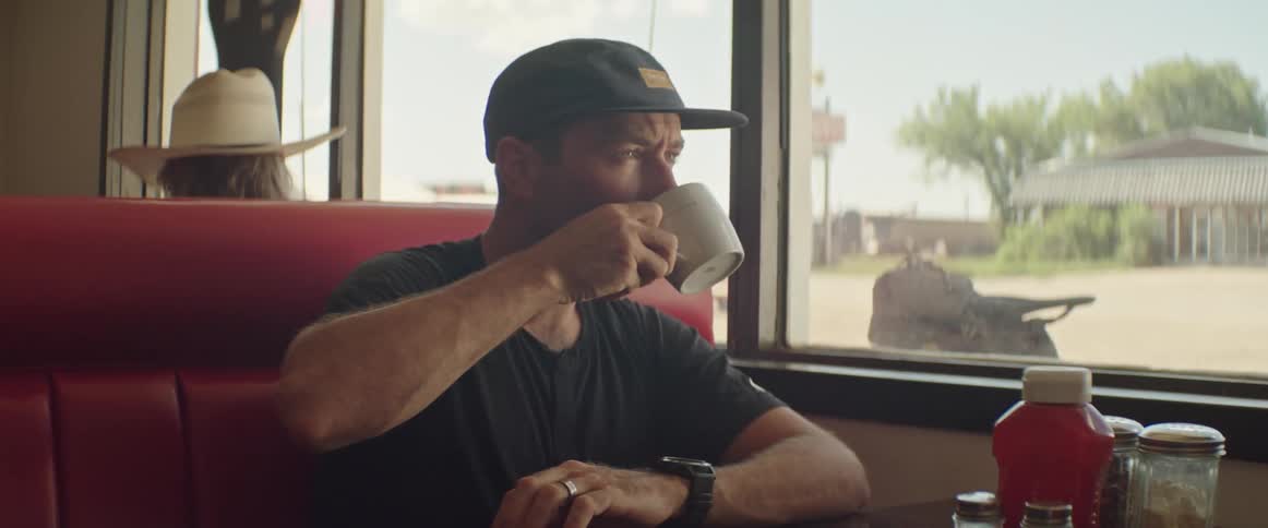 A man sips coffee while looking out the window of a restaurant