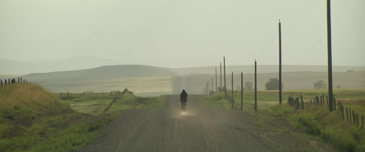 Male cyclist with helmet riding down dirt road in the countryside