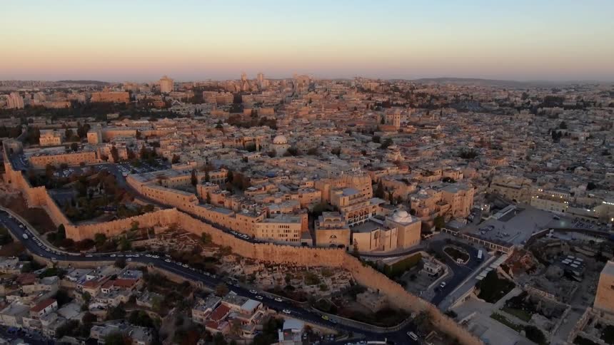 A city has many buildings and cars traveling at sunset
