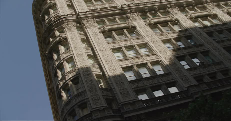 A building with a lot of detail is in a city with taller skyscrapers