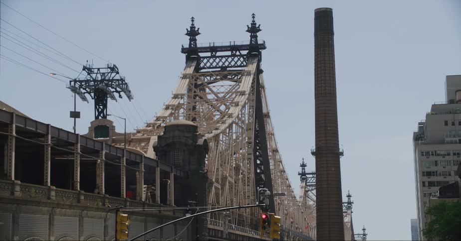 Large bridge sits in city bordered by a red traffic light and tall powerline tower