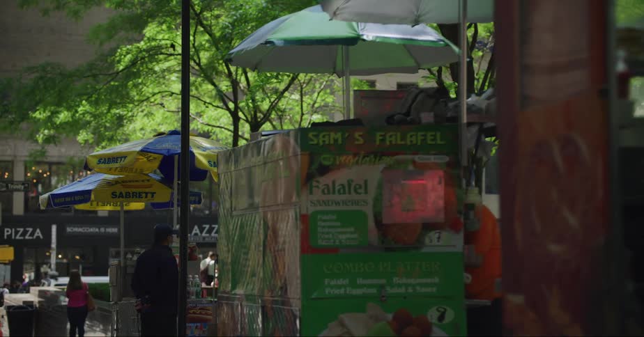 Vendors selling food line a city street with people walking and shopping