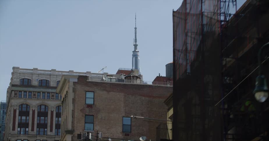 Antenna on the top of a tall skyscraper in the city skyline at daytime seen from a moving vehicle
