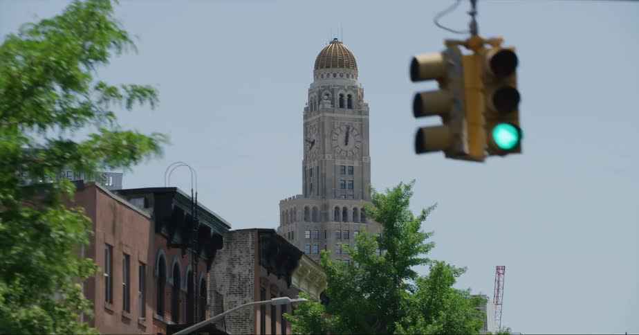 The williamsburgh savings bank tower standing above brick apartment buildings and tree lined street