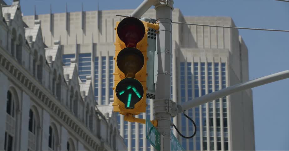 A traffic light changes on a downtown street with buildings in the distance