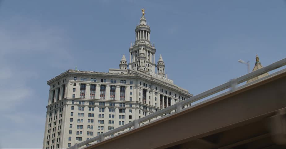 The manhattan municipal building and a tower can be seen over the bridge
