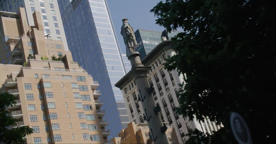 A statue sits on a tall post in the heart of downtown