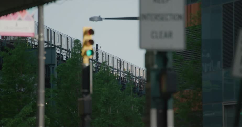 Passenger train running on track seen from vehicle driving on highway with signs and traffic lights in the city
