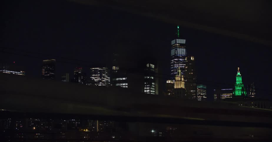 Illimunated skyscraper with spire and high rise buildings at night in the city