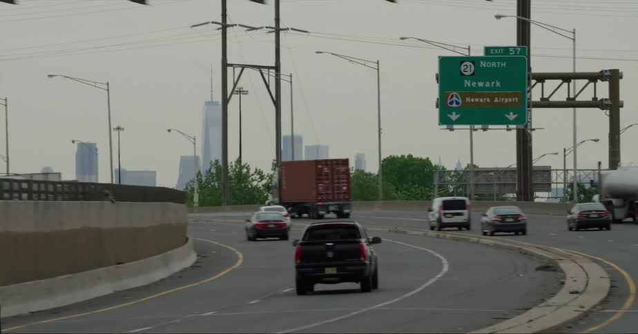 Vehicles driving on the highway towards the city skyline at evening