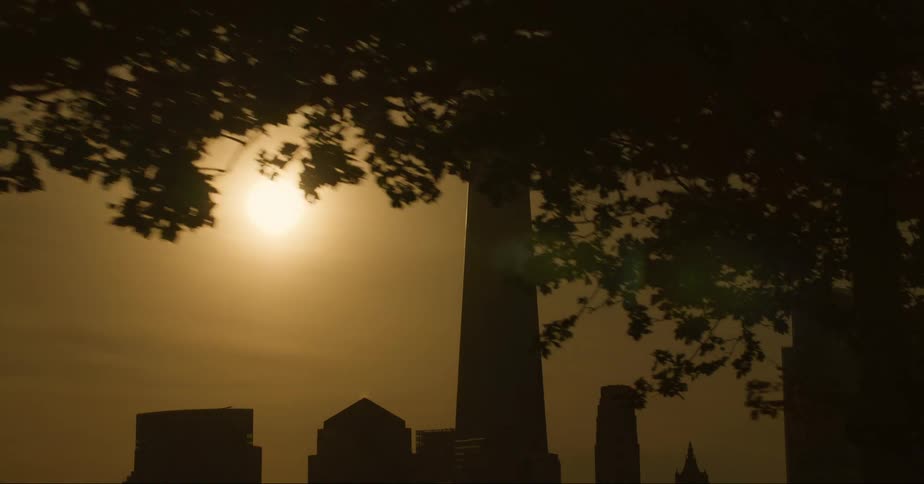 A towering skyscraper with a tall antenna stands towering above several nearby buildings