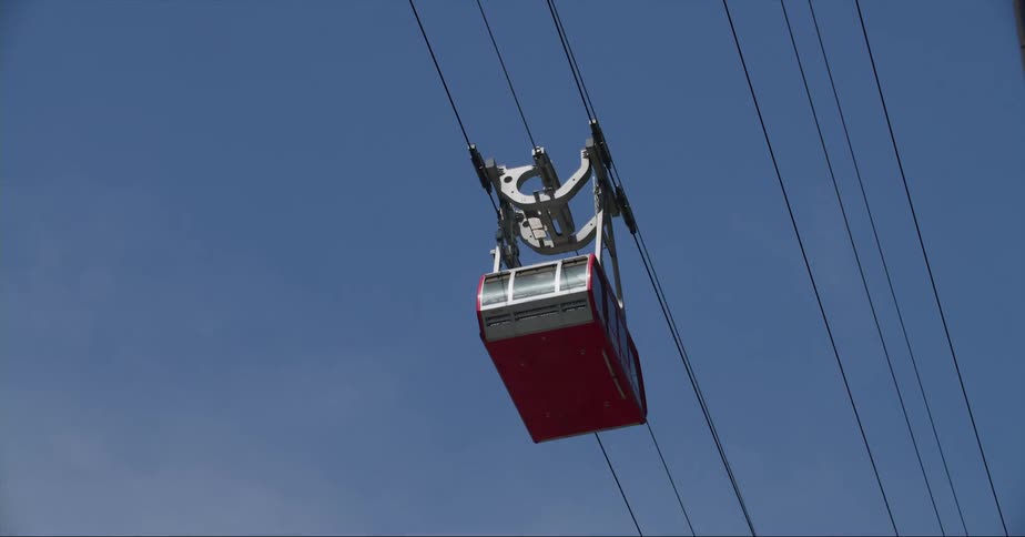 A gondola that carries people moves along cables above the city streets