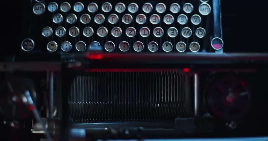 Close up of a red and blue light reflecting on the keys on a vintage typewriter keyboard