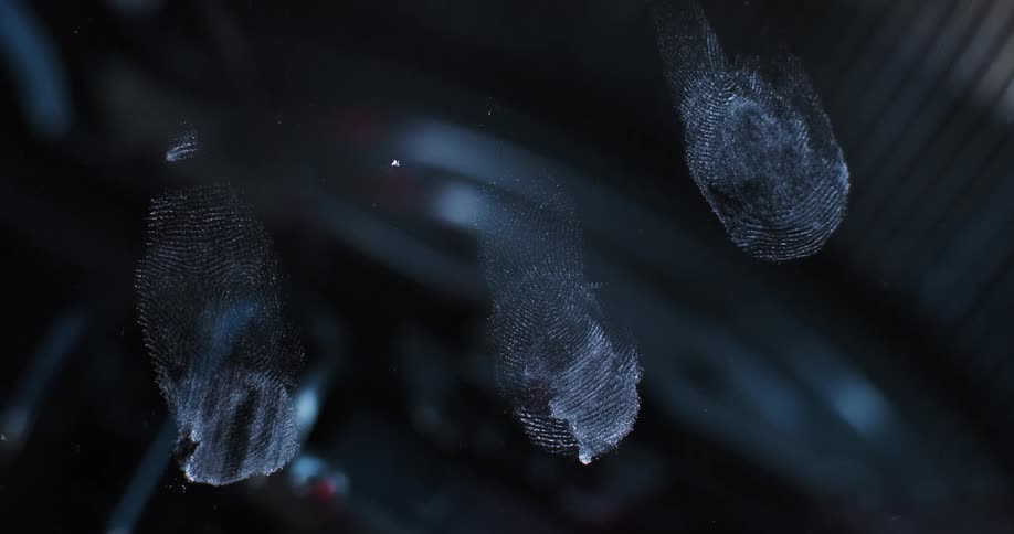 Flashing red and blue lights shine across fingerprints on glass as nearby objects move
