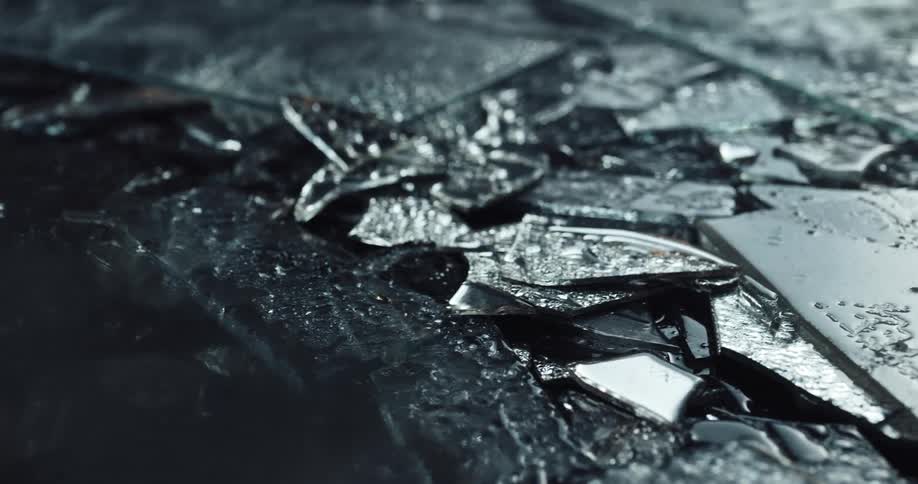 Close up of fragments of broken glass with police lights displaying on