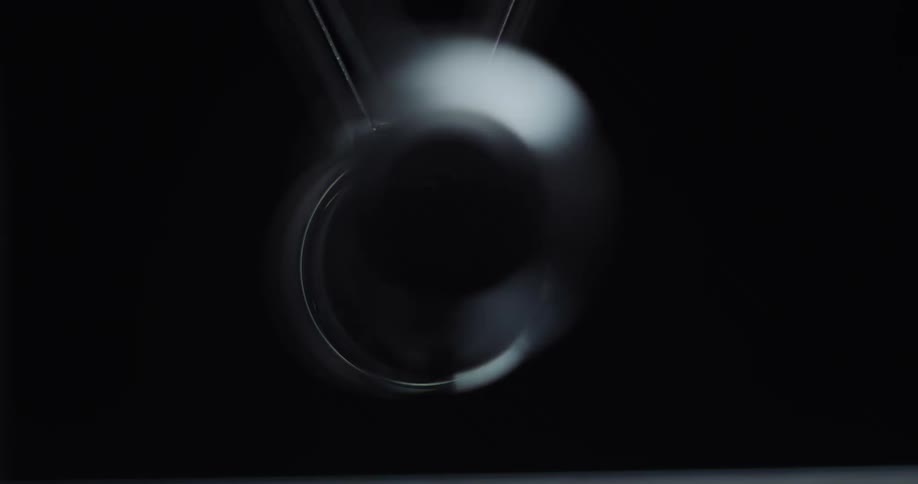 Metal balls are swinging back and forth in the darkness hitting each other in a newtons cradle