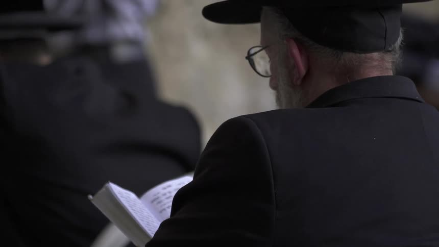 Man in a black hat reads a book