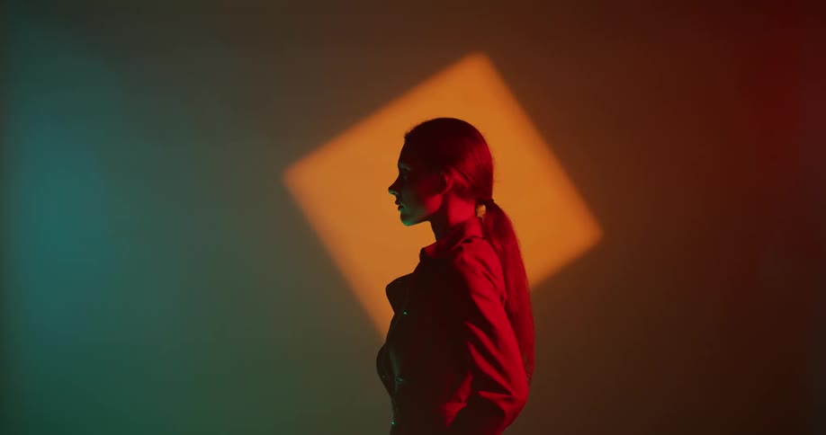 A woman is posing with dramatic light as a backdrop