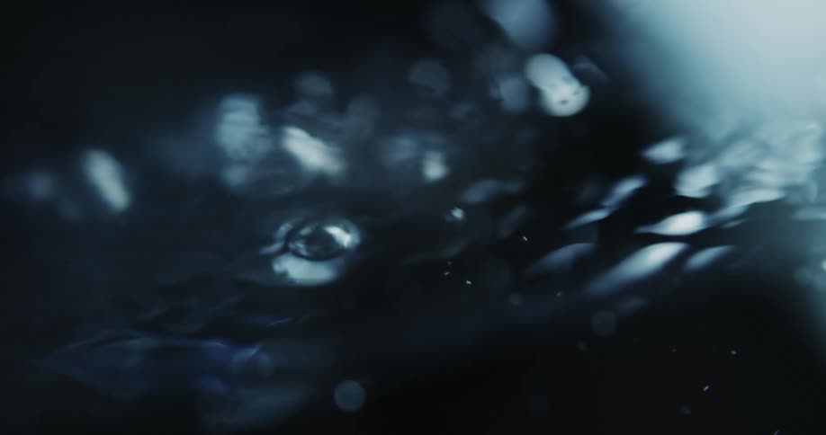 Close up of tiny air bubbles rising to the water surface on a dark environment