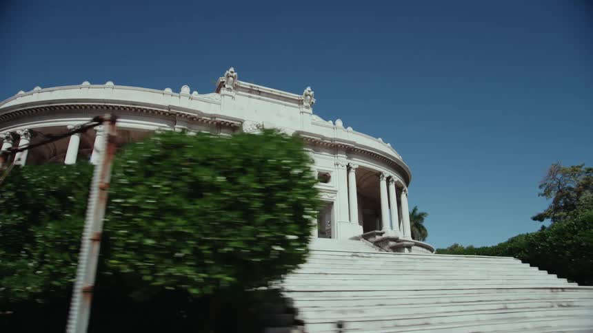 Two women are walking up the steps of a round building with an arch