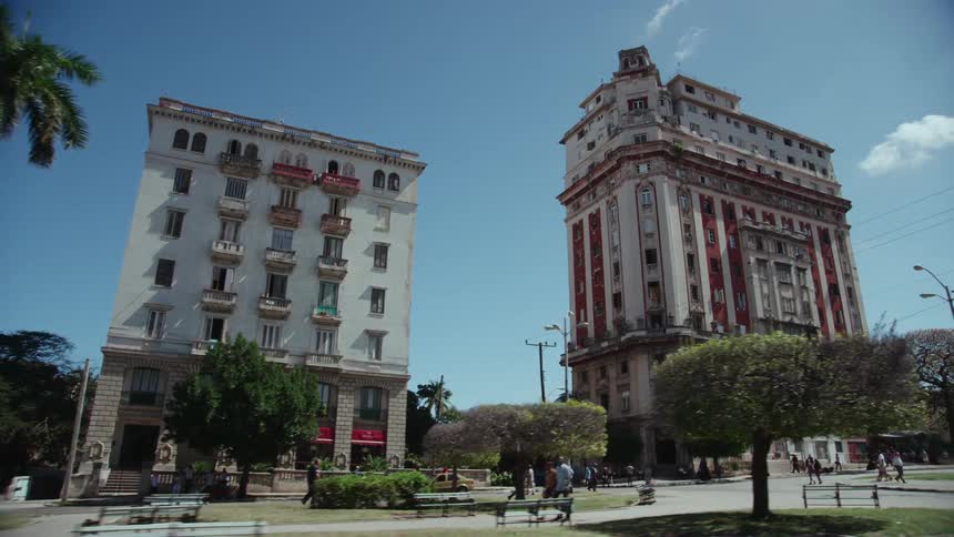 People walking through the park near buildings on avenida de los presidentes in havana cuba on a sunny day