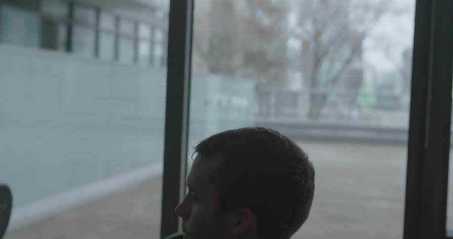 A man lifts weights in front of a window