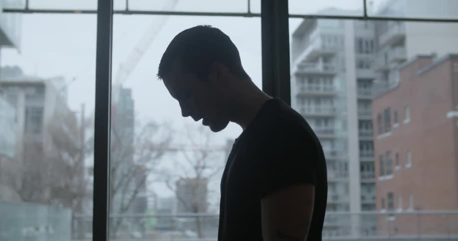 A man in a black shirt is breathing heavily and looks up