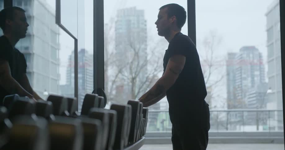 A man lifts two barbells from a rack