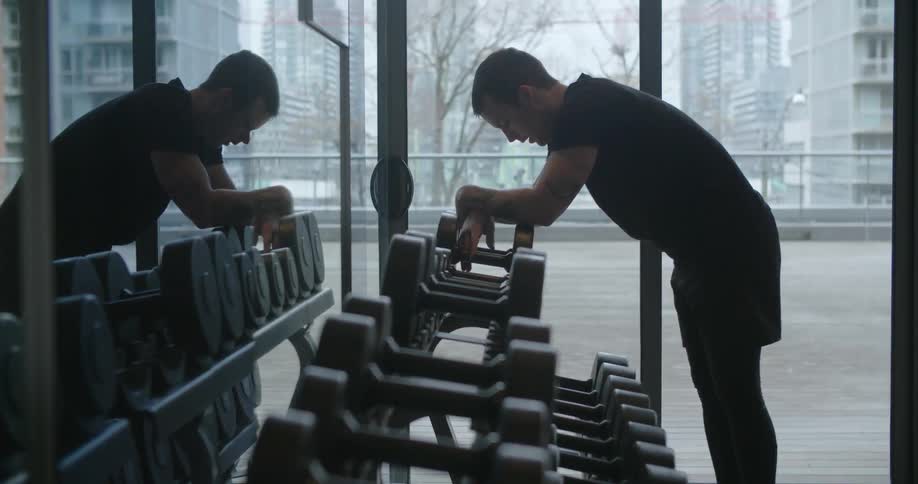 A man leans on a weight rack