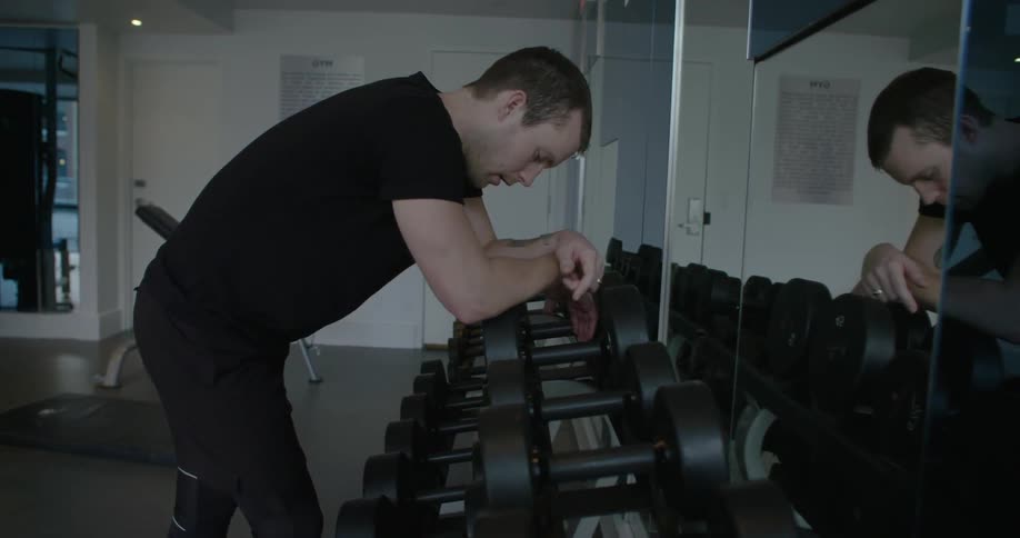 Man bending over as he rests on equipment in a gym