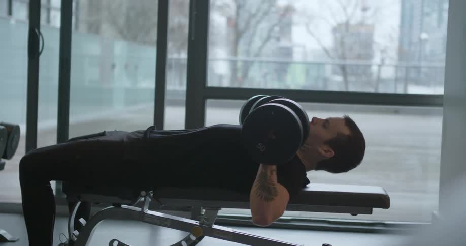 A man lays back with two weights and lifts