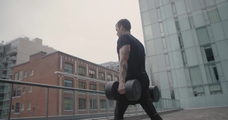 Man walking while holding large dumbbells