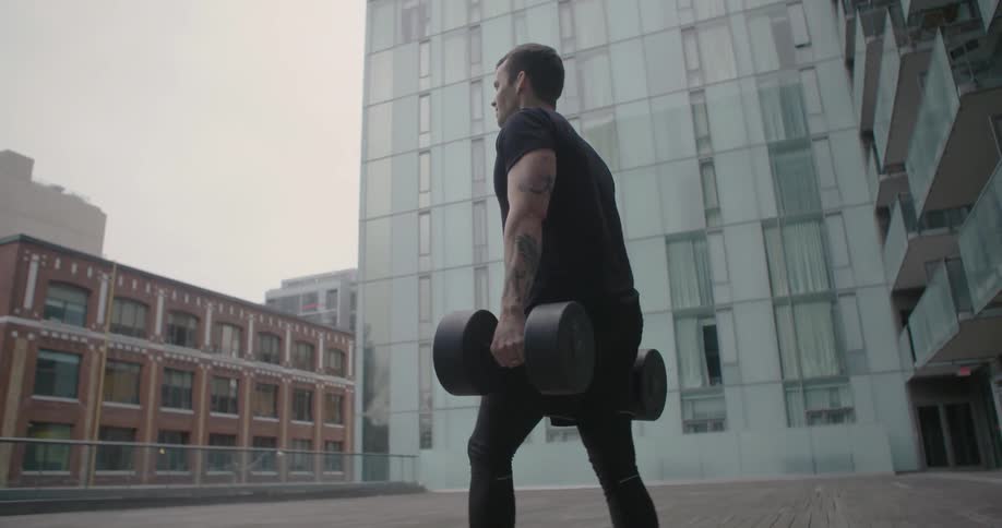 A man is carrying two huge barbells as he walks outside