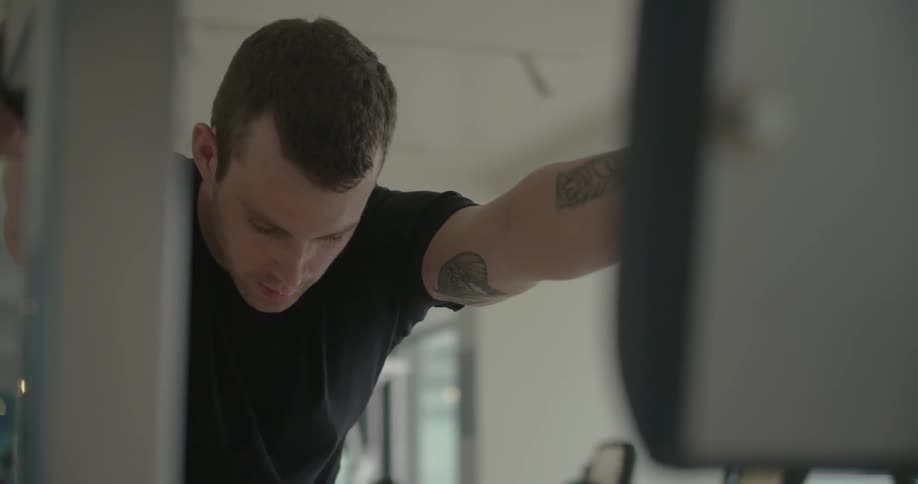 A man breathes heavily and drips sweat in a gym