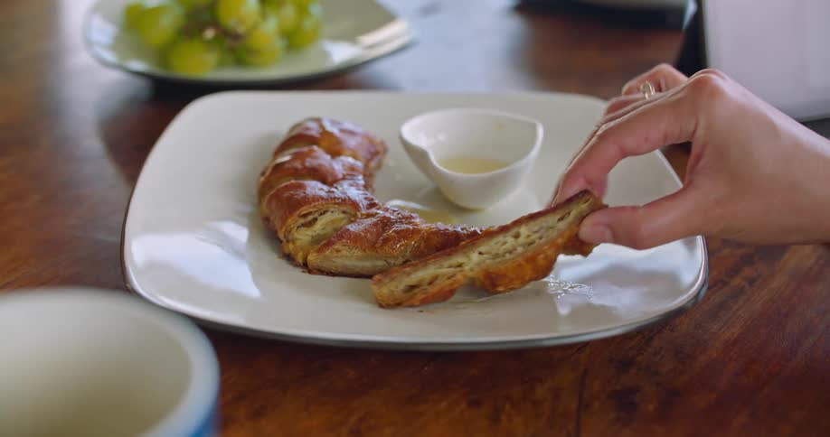 A woman picks a piece of bread up from a plate