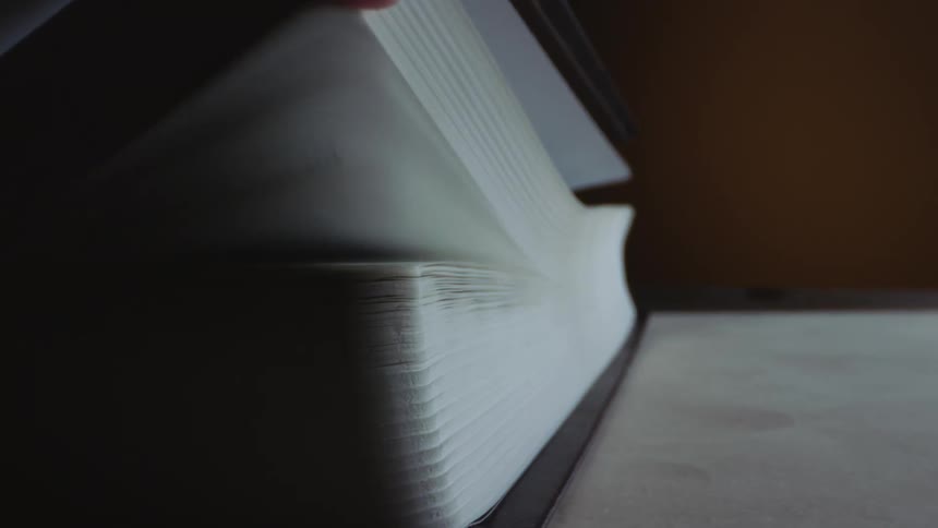 Person runs fingers along edge of book ruffling the pages