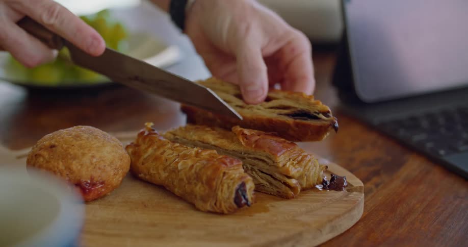 A woman cuts a croissant on a cutting board