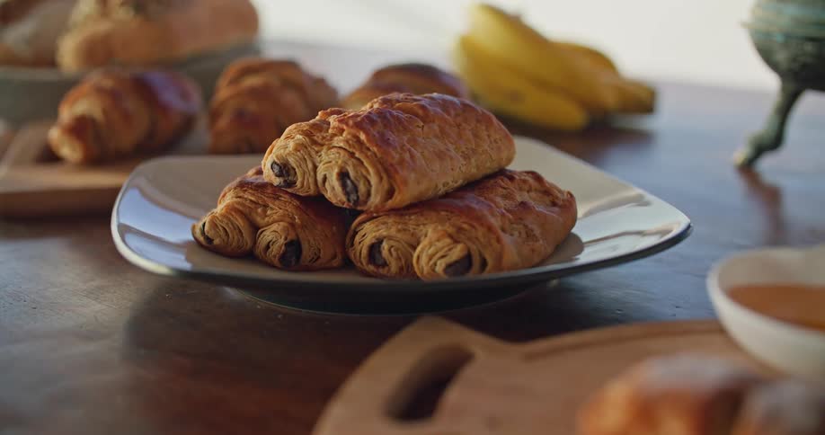 Pain au chocolat on plate on the table with croissant and banana