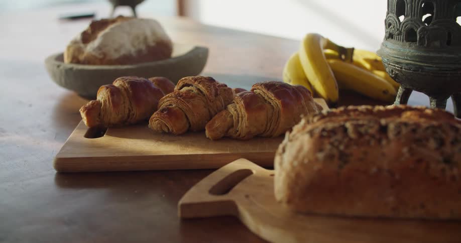 Bread and croissants resting on wooden boards over a table