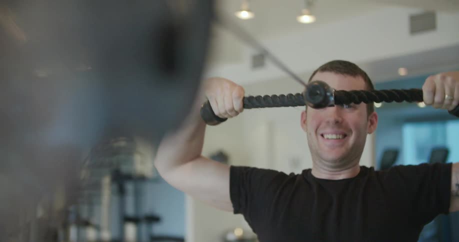 A man works out using a weight machine at the gym