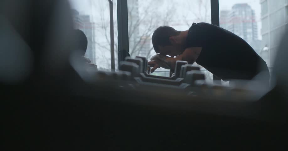 A man leans on some weights in a gym