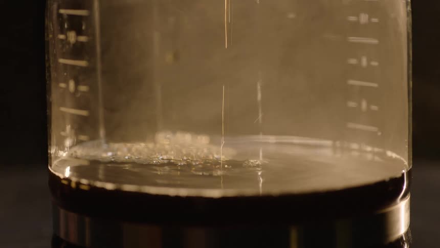 Camera slow orbits coffee dripping into pot