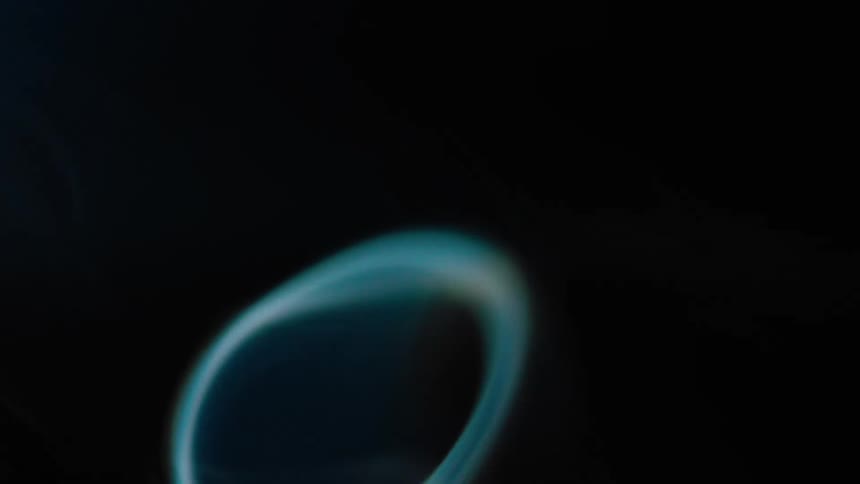 Thin gassy shapes rise and flow against a black background