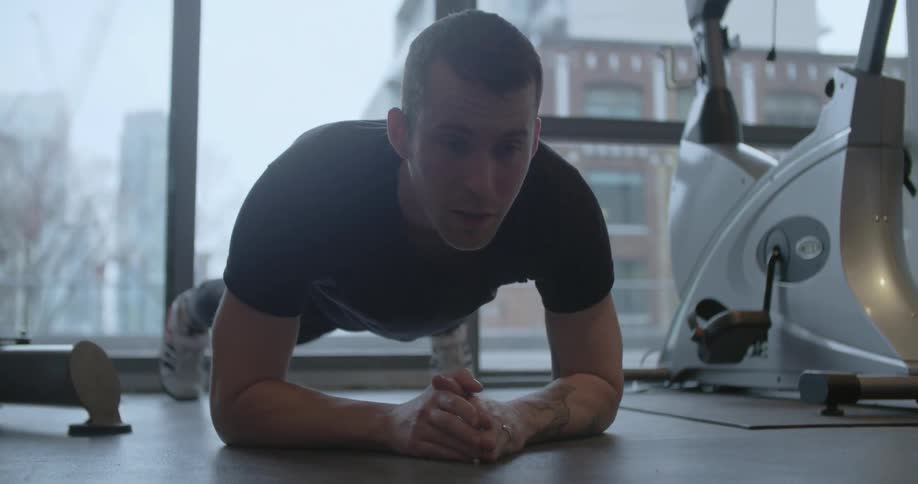 A man does a plank in a fitness room
